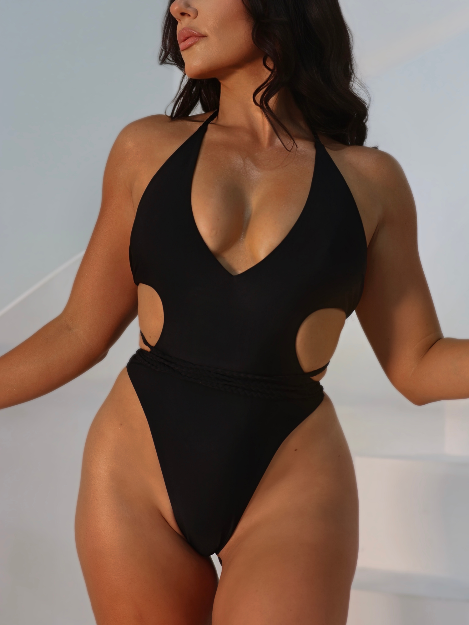 Woman wearing a black swimsuit with cut-out design against a neutral background